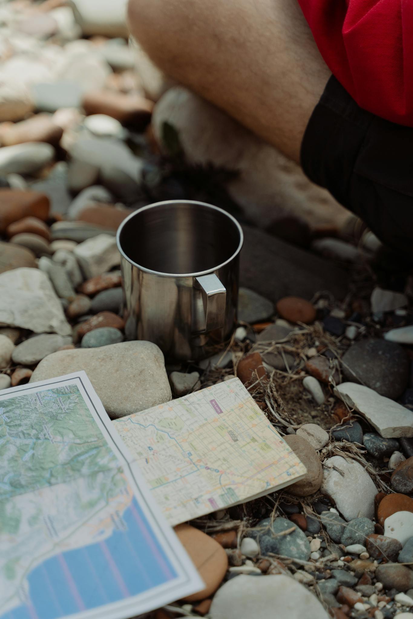 A tranquil outdoor setting with a map and a metal mug on rocky terrain, ideal for hiking themes.