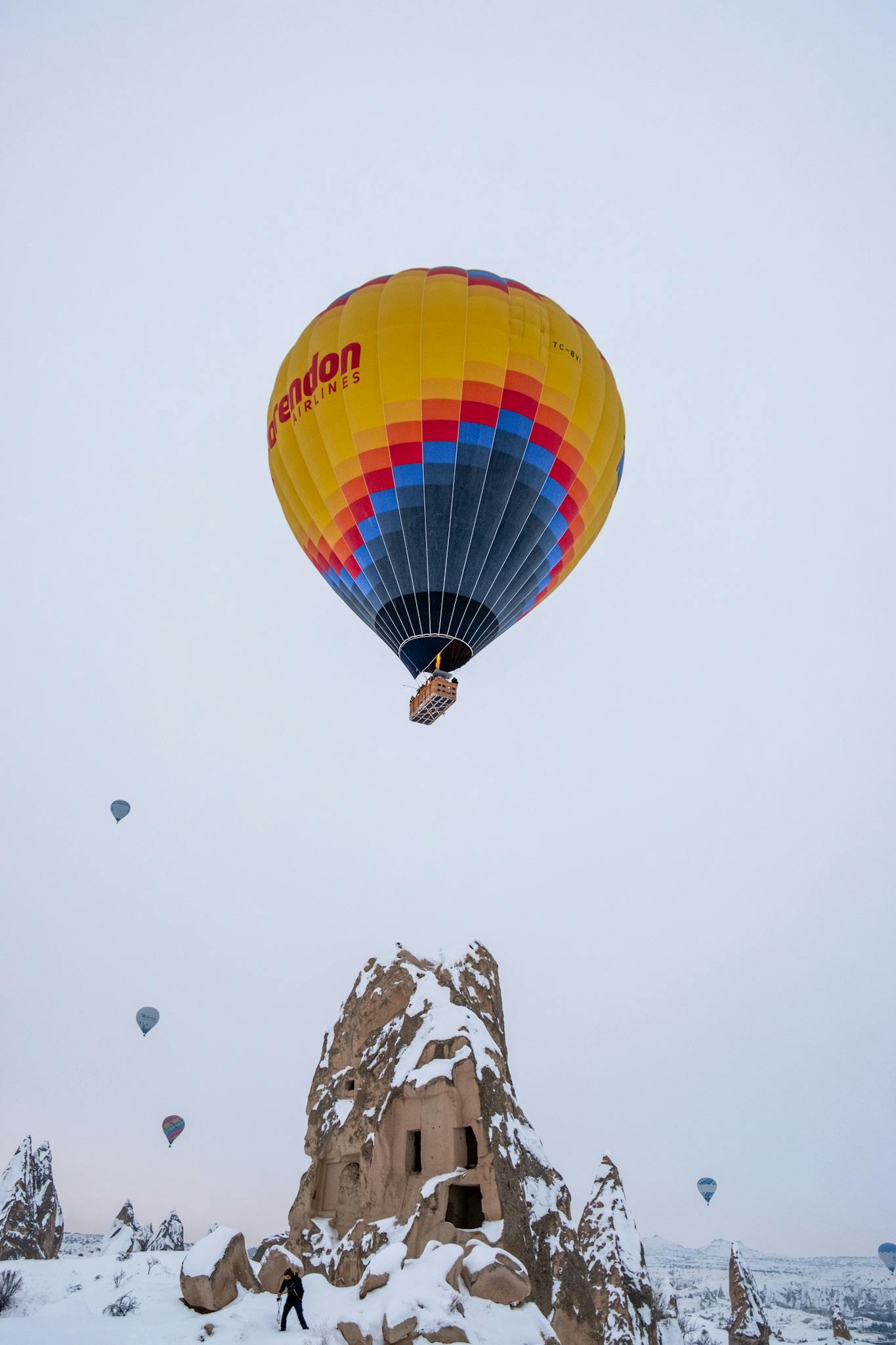 Colorful hot air balloons soaring over snowy fairy chimneys in Cappadocia.