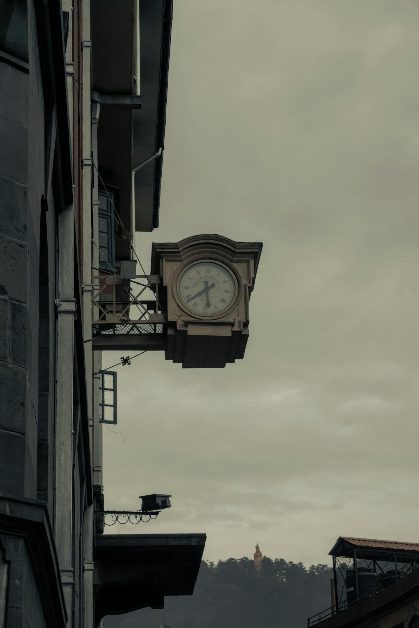Old clock on a building in Shimla, India against an overcast sky.